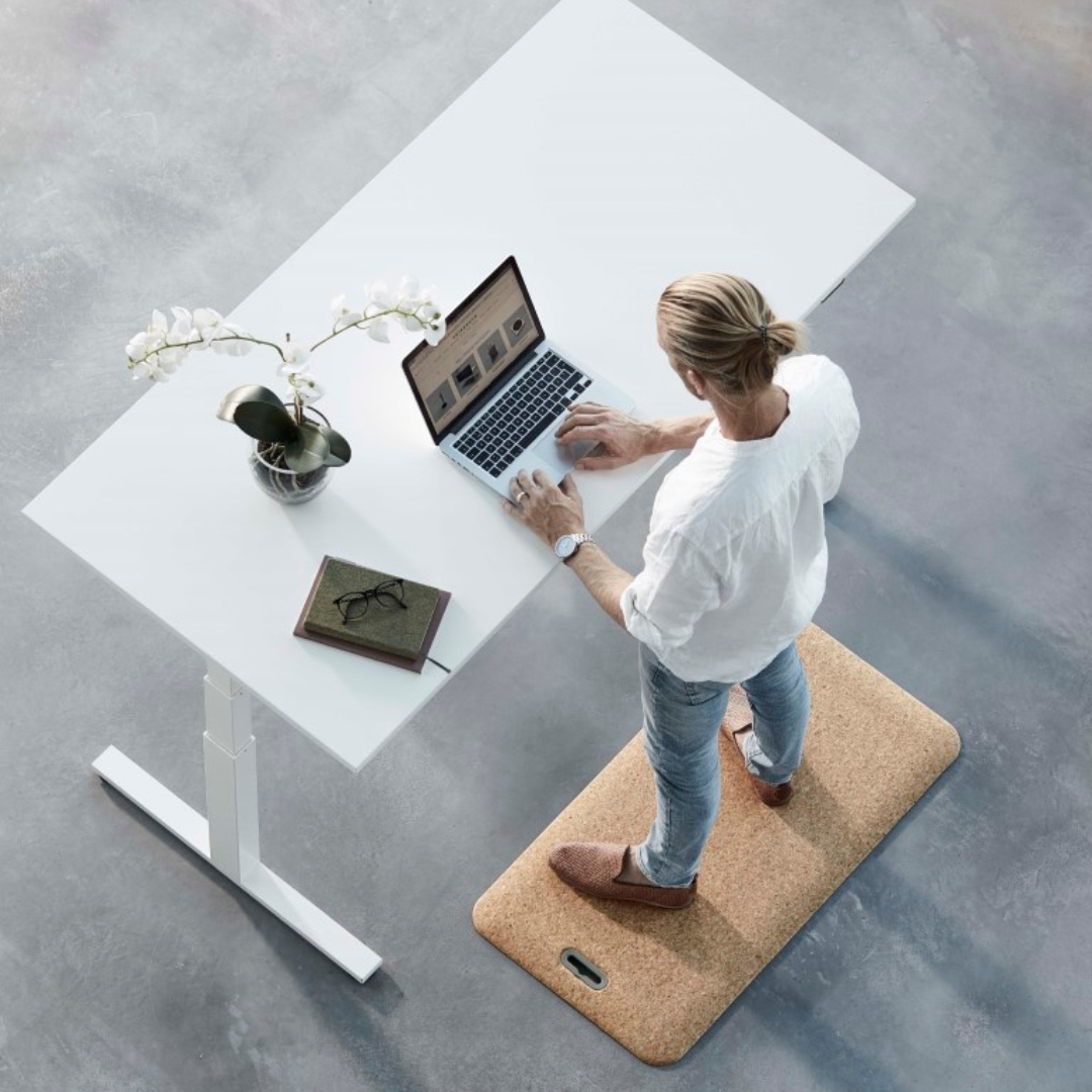 Använd dina nya produkter - man som står på en ståmatta framför sitt höj och sänkbara skrivbord
